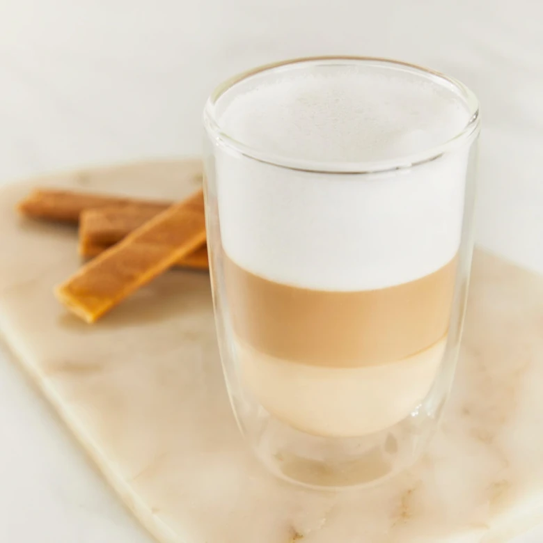 Vrstvené latte v sklenici s kořením na mramorovém podkladu.