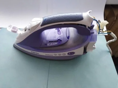 Rozložená žehlička značky Tefal s viditelnými vnitřními součástkami.