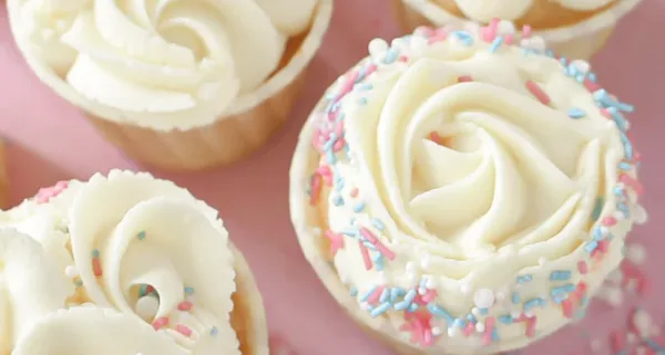 Muffiny s bílým krémem a barevnými cukrovítky.