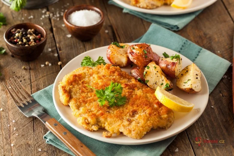 Zlatavý smažený řízek s bramborami citronem na talíři