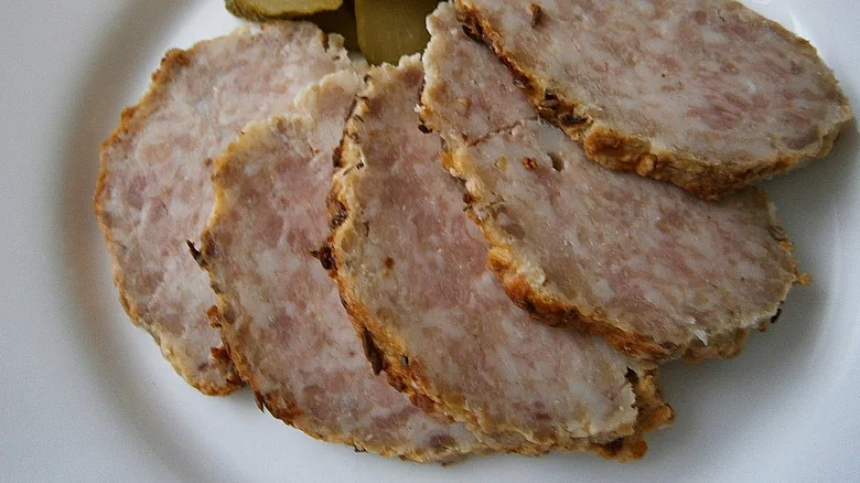 Nakrájený pečený masový koláč na bílém talíři.