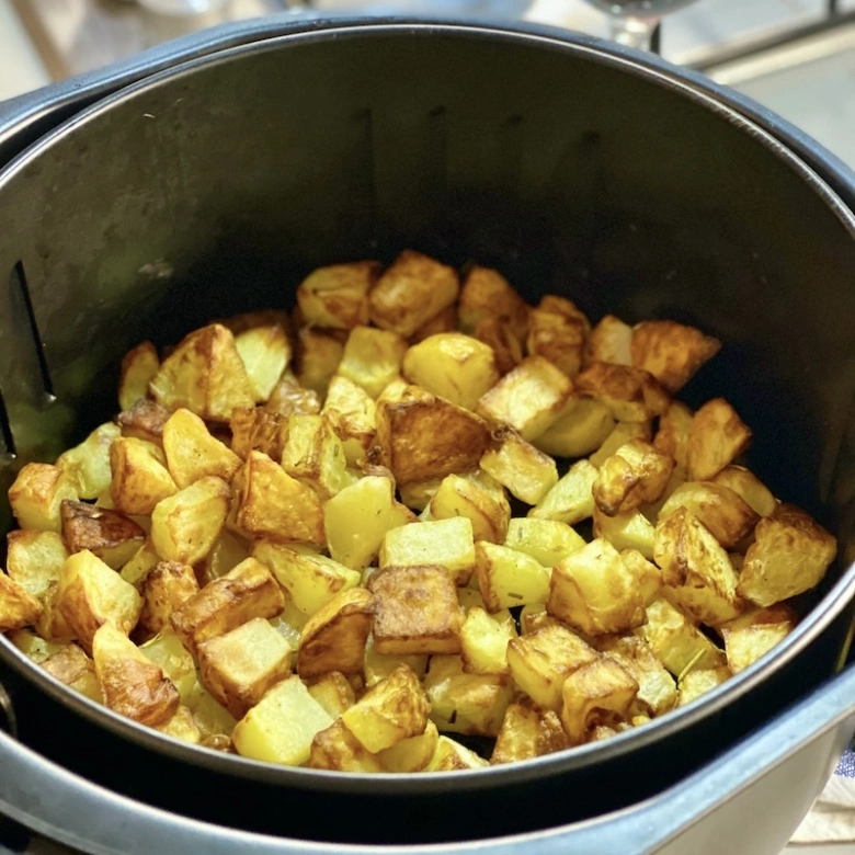 Zlatavé kousky brambor upečené ve fritéze s křupavou povrchovou vrstvou.
