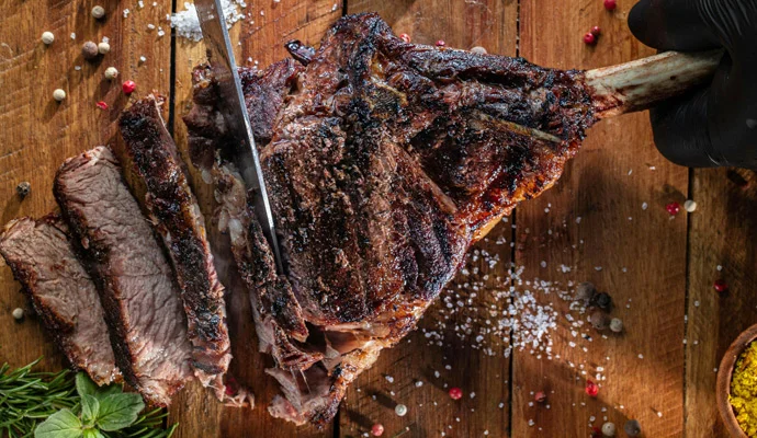Opečený steak na dřevěném prknu s viditelnými stupni propečení.