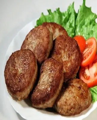 Připravené řízky na talíři s okurkou a rajčaty.