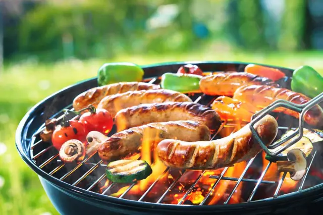 Grilované klobásy s zeleninou na grilu venku.
