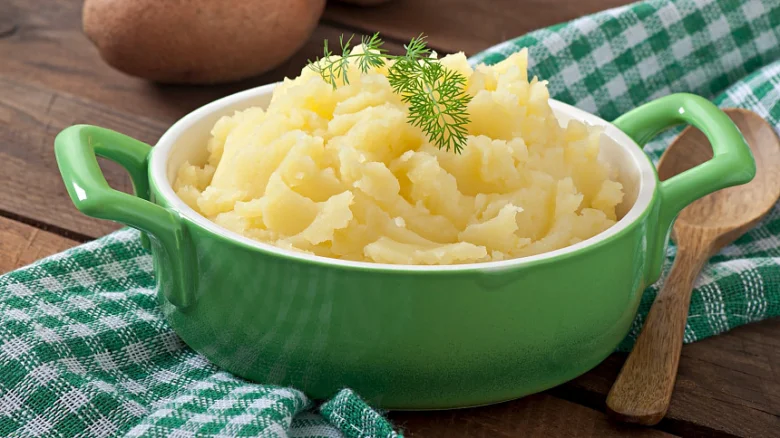 Zelená miska s bramborovou kaší, petrželkou a celými bramborama.