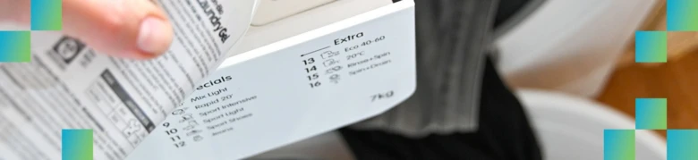 Ruka drží ovládací panel pračky s nastavením programů.