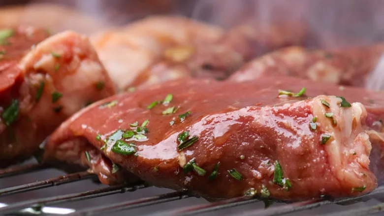 Marinované maso na grilu připravené k pečení.
