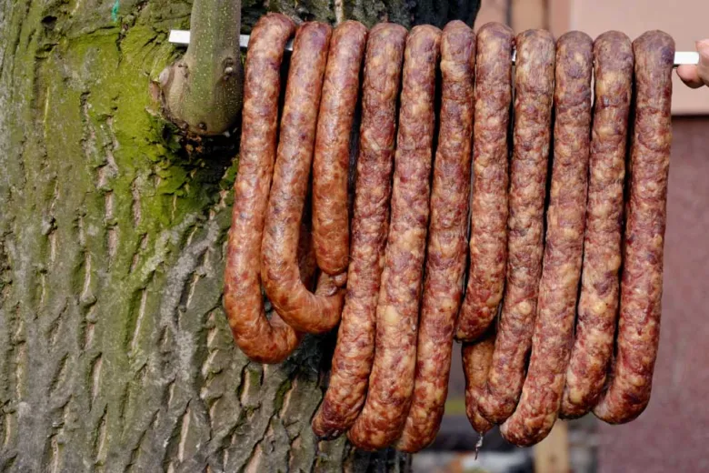 Domácí klobásy visící na stromě po uzenění nebo sušení.