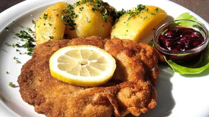Smažený řízek s citronem a bramborami na talíři
