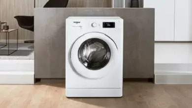 Bílá pračka v interiéru s dřevěnou podlahou.