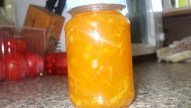 Sklenice s domácí pomerančovým džemem na kuchyňské desce.