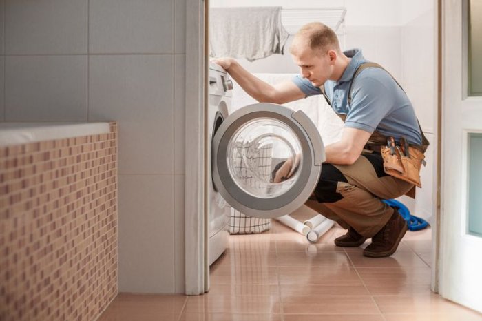 Technik opravuje pračku Whirlpool v koupelně.