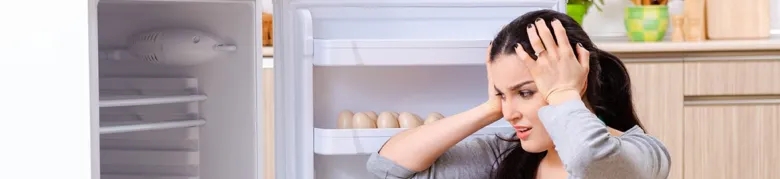 Žena se dívá do prázdné lednice s vejci.