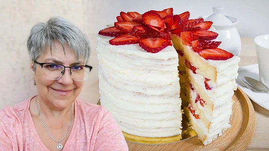 Žena stojí vedle vysokého dortu s piškoty a jahodami.