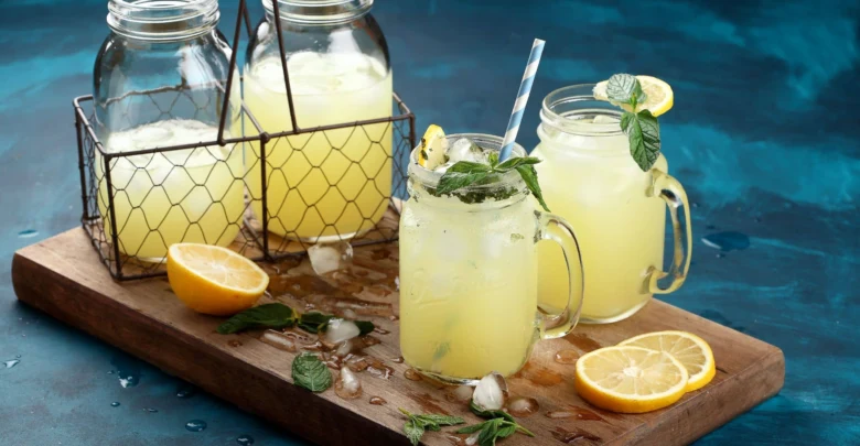 Domácí limonáda s citronem a mátou v džbánku na dřevěném podnose.