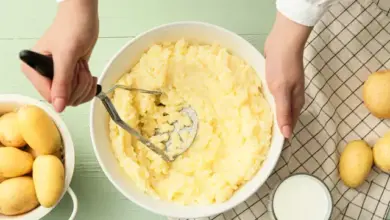 Osoba třepí vařené brambory v míse s hrnčákem.