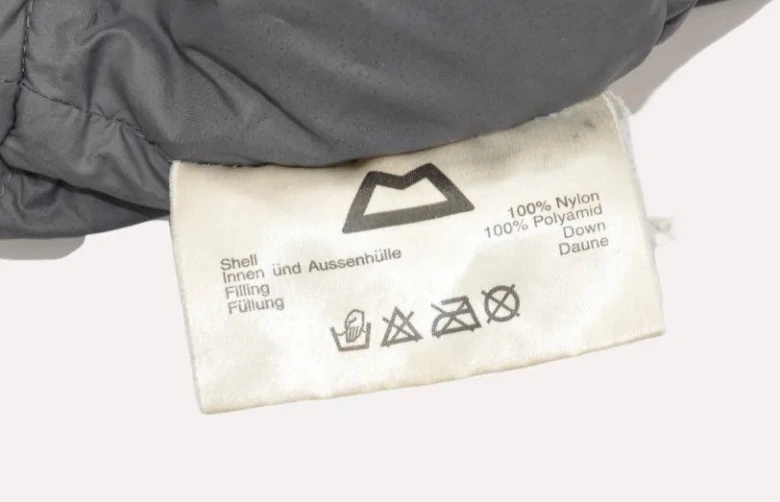 Štítek s informacemi o materiálu a symboly pro praní spacáku.
