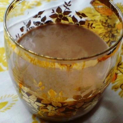 Sklenička s hnědým nápojem na žlutém ubrusu