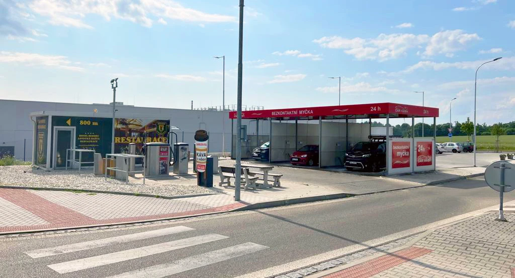 Samoobslužná myčka s vozy v bayech a značkami na venkovním parkovišti.