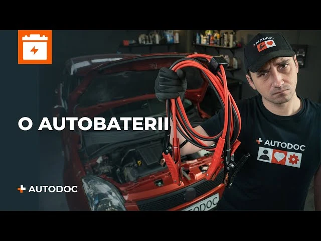 Muž drží červené kabely pro připojení k baterii u otevřeného motoru vozu.