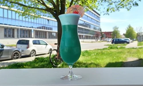 Modrý koktejl s ozdobou na venkovním stole.