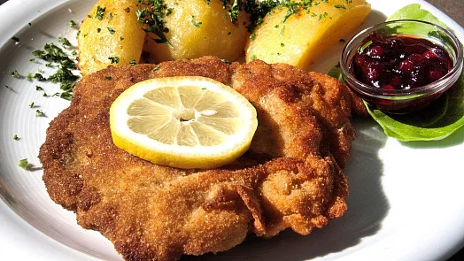 Smažený řízek s citronem, bramborami a brusinkovou omáčkou.