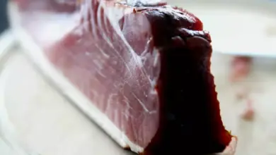 Kousek uzeného masa s viditelnou marmurací na řezacím prkně.