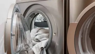 Otevřená pračka s ručníky uvnitř vedle dalšího zařízení.