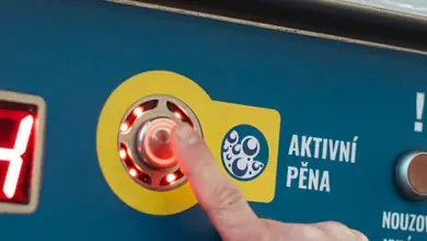 Ruka tlačí na knoflík aktivující pěnu v samoobslužné myčce.