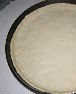 Surové listové těsto rozložené na pekáči před vařením.