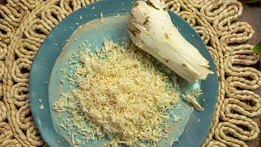 Celý křen vedle nastrouhaného kořene na modré talíři