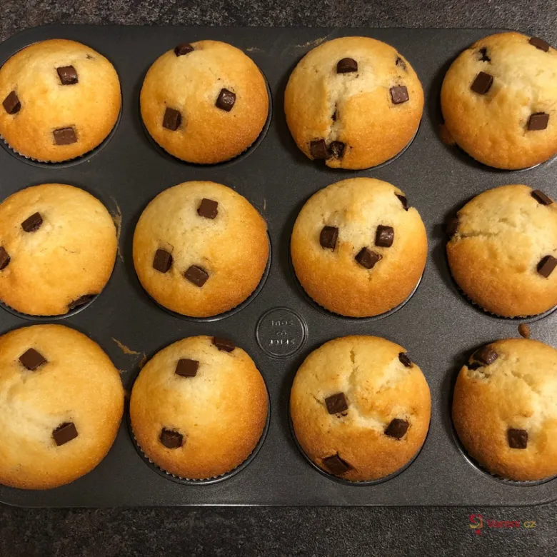 Zlatohnědé muffiny s čokoládovými kousky v pekáči.