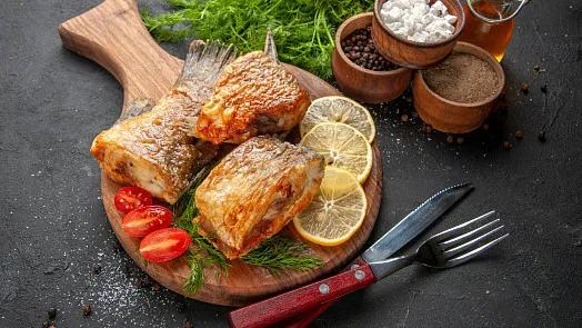 Uzená ryba s citronem na dřevěném talíři.