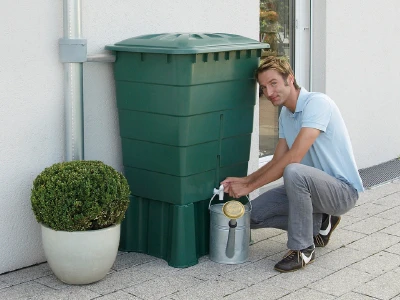 Muž naplňuje kbelík z nádrže na dešťovou vodu pro zahradu.