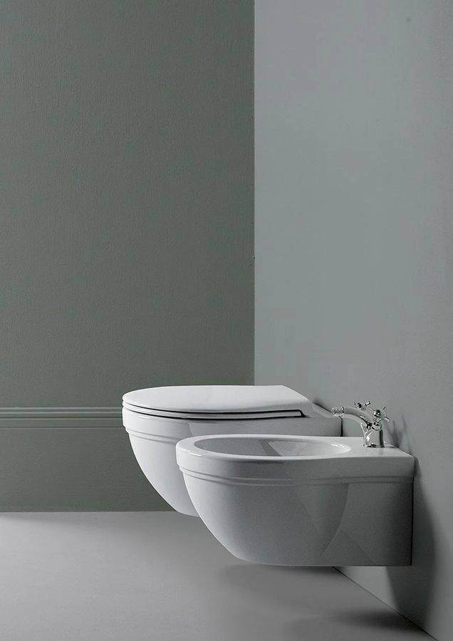 Bílé zdi s umyvadlem pro sprchování vedle WC.