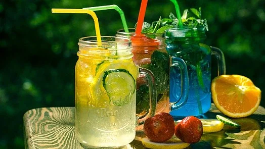 Tři barevné domácí limonády s ovocem v džbánkách venku.