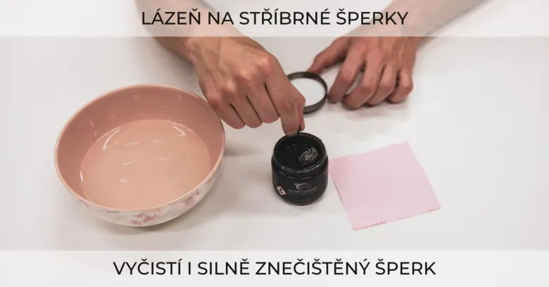 Ruční aplikace čističe na stříbrný šperk v míse s vodou.