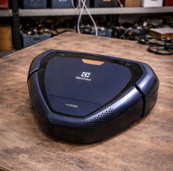 Modrý robotický vysavač značky Electrolux na dřevěném stole.