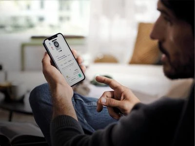Muž používá chytrý telefon pro ovládání domácího spotřebiče.