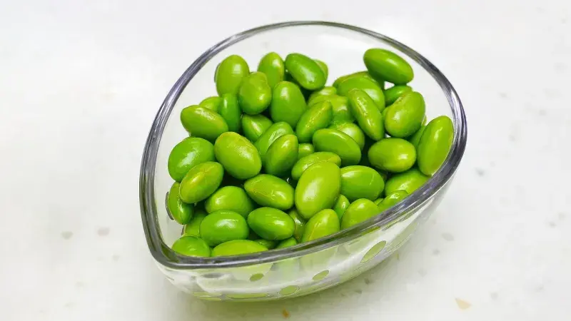 Skleněná miska plná zelených vaječných fazolí edamame.