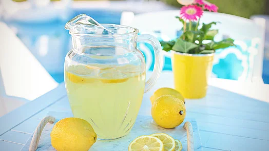 Sklenice s domácí limonádou na modrém stole.