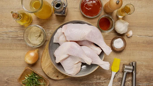 Surová kuřecí stehna s ingrediencemi pro grilování nebo pečení.