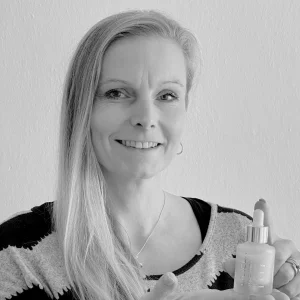 Žena drží lahvičku s barvou na vlasy v ruce.