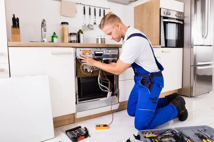 Technik opravuje myčku nádobí v kuchyni s nástroji.