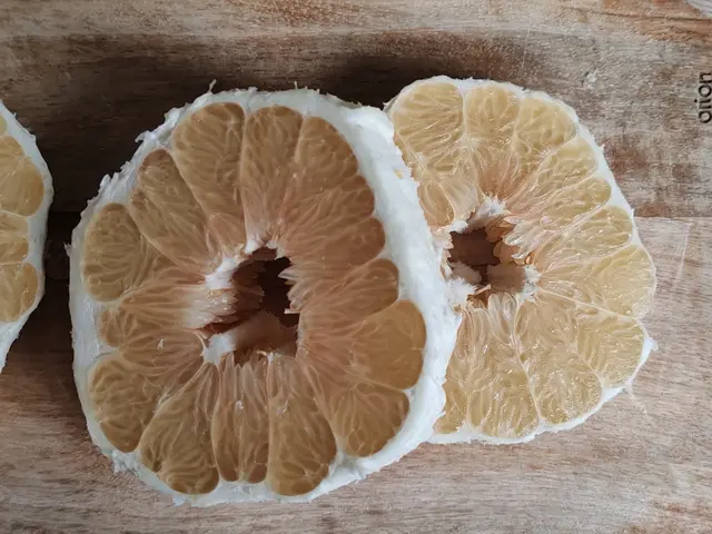 Dva loupané poloviny grapefruity na dřevěném povrchu.