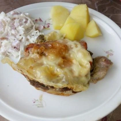 Pečené maso sýrovou omáčkou, brambory a salát z kapusty.
