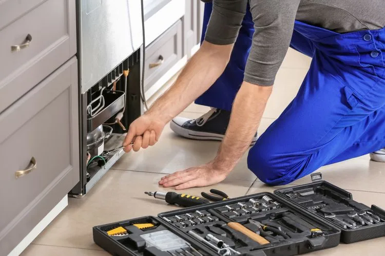 Technik opravuje vestavěnou lednici s použitím nářadí.