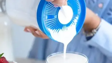 Lidé nalévají mléko do sklenice pro domácí kefír.