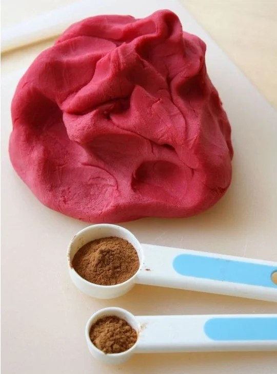 Červená domácí plastelína s lžičkami koření pro recept.
